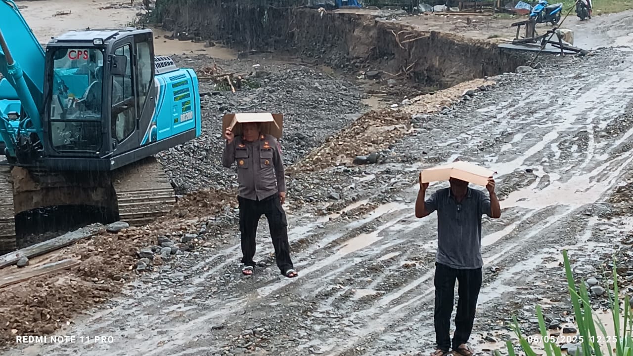 (Foto:Kapolsek Urban Kotabunan, AKP Budi Priyanto, S.Sos., yang turun langsung mengawal proses Kawal Langsung Perbaikan Jalan Kotabunan,Bukaka Meski Diguyur Hujan)